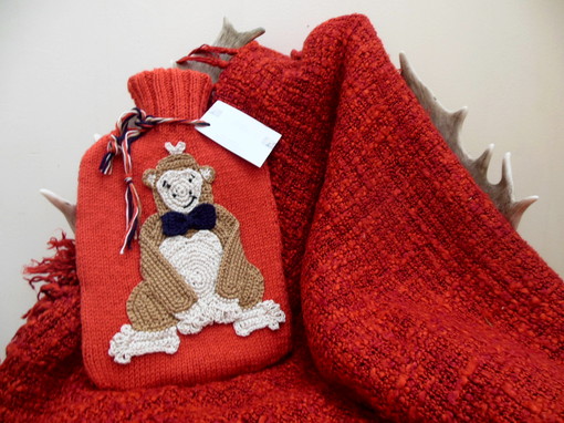 Hot water bottle cover with a gorilla applique placed on a blanket over a chair.