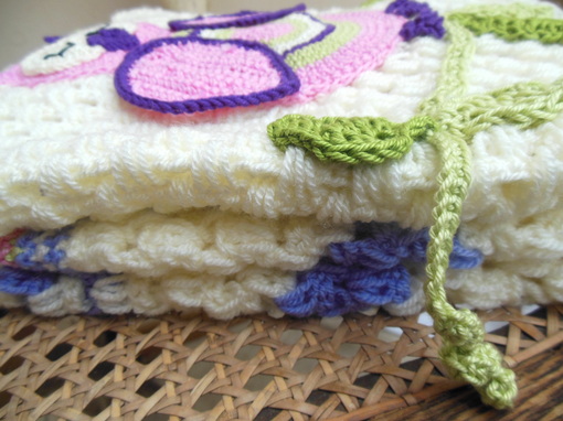 Close up of the blanket folded on a chair showing the thickness of the premium wool and crochet stitch.